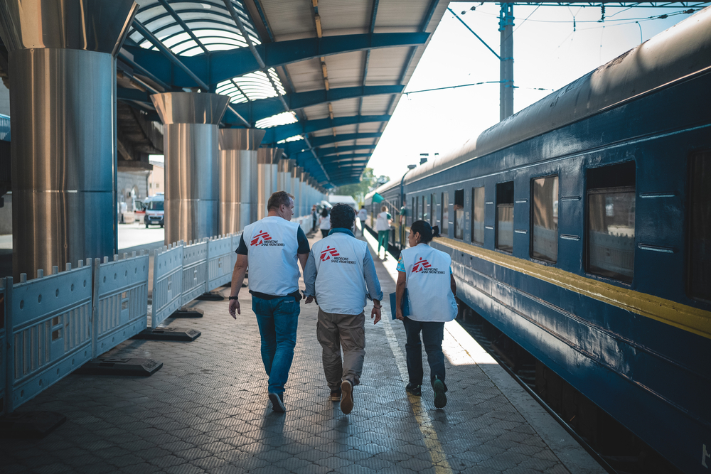 Three MSF international staff walking past a medical train