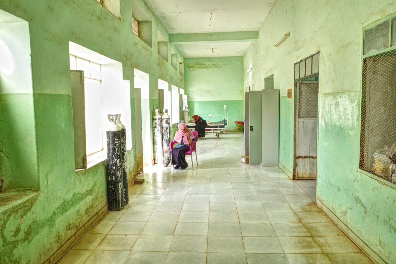 Patients sit in the corridor of the MSF-supported Umdawanban hospital in Khartoum State.