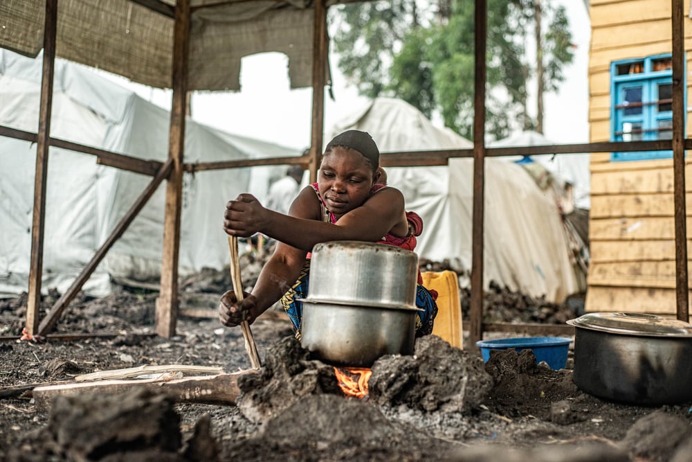 Woman prepares food over fire