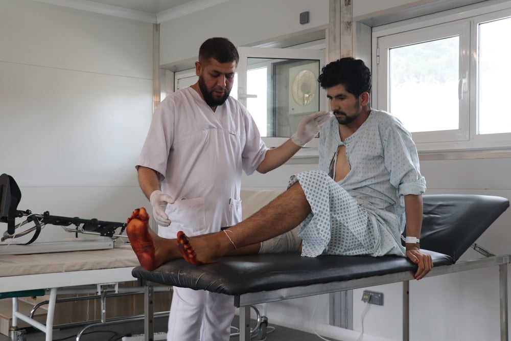 An MSF physiotherapist helps a patient with leg exercises in the physiotherapy department of the MSF Trauma Centre in Kunduz Province. Baryali, 23, sustained a gunshot wound to his left leg, resulting in a fractured femur that was treated with external fixation. 