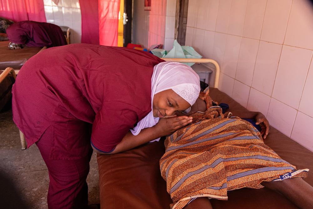 Agnes Okpahe, a Nigerian Ministry of Health midwife, uses a foetoscope to check a woman in labour at the primary healthcare facility in Aujara village, Jahun, Jigawa state. December 2023. © Abba Adamu Musa/MSF  