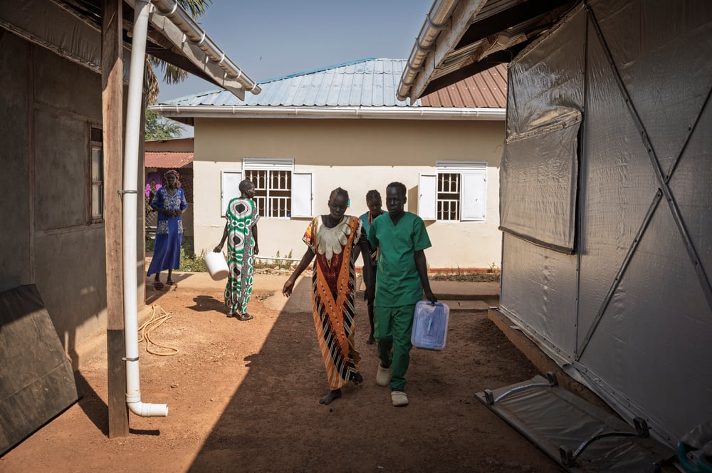 A midwife guides a woman in early labour toward the maternal unit 