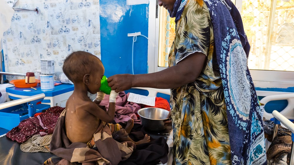 A Mother feeds her severely malnourished son