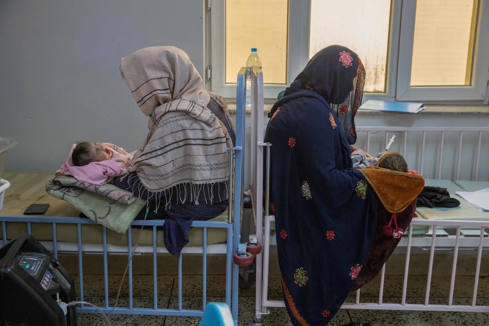 Two mothers carrying their children in the New Natal Ward.