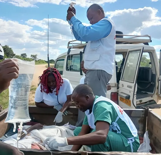 MSF staff treating a patient in a scotch cart on the road side
