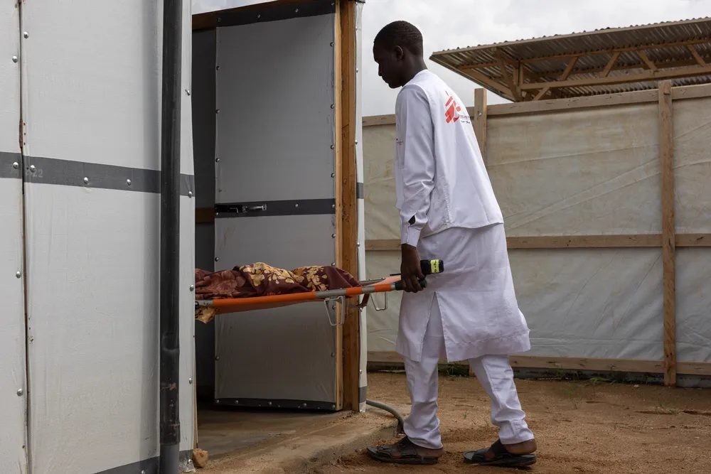 The body of a 10-year-old child is carried into the morgue at the MSF Hospital in Metche