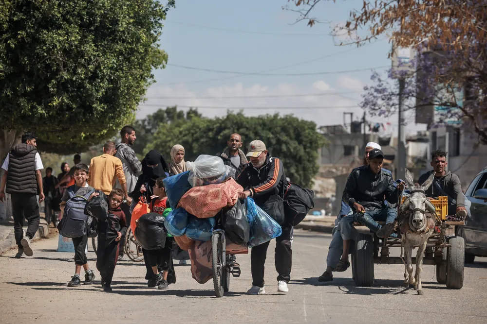 Displaced Palestinians in Rafah carry their belongings