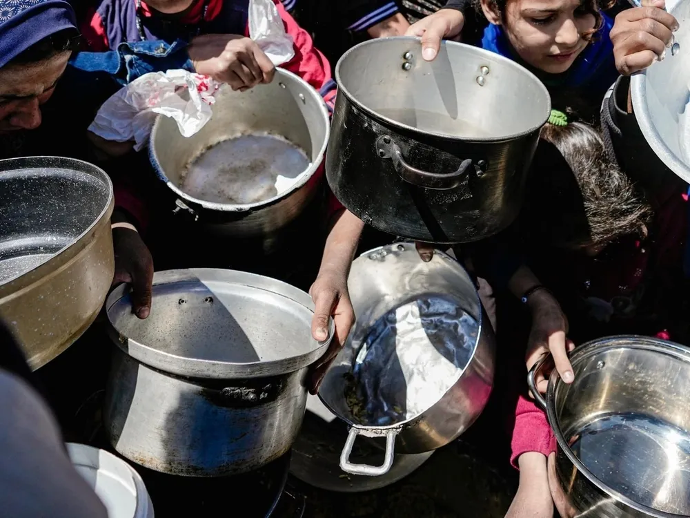 Children hold empty pots at a community kitchen in northern Gaza