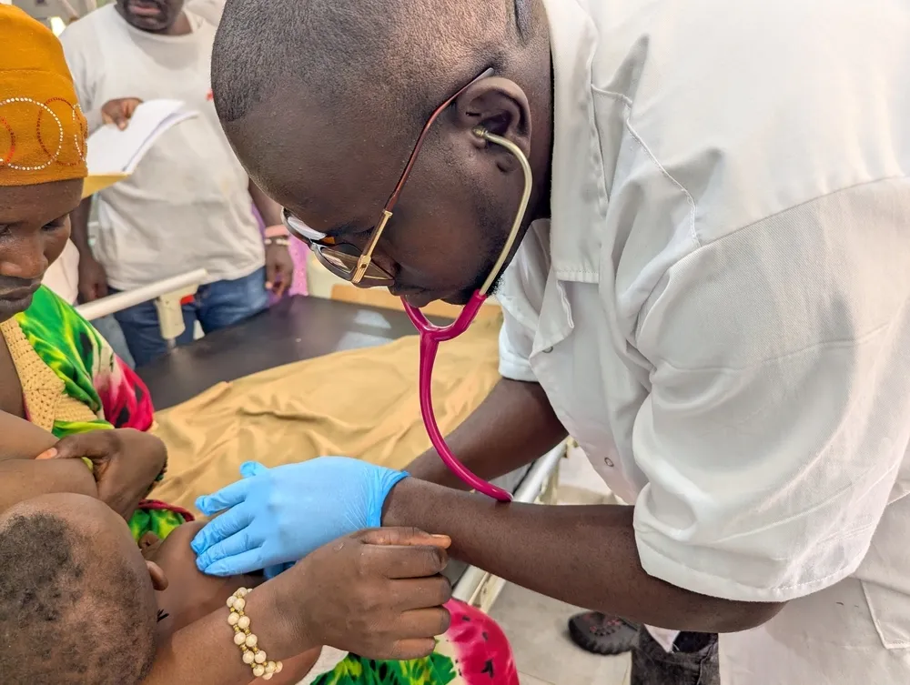 a doctor from the Ministry of Health examines a child sitting on his mother’s lap