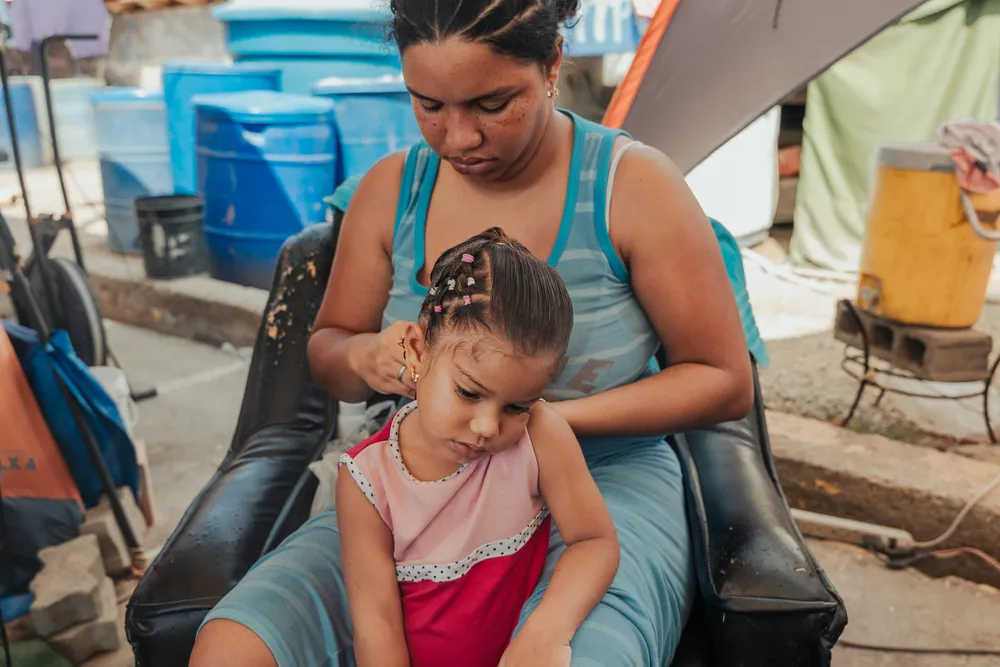 Greydiel Álvarez, 22, braids three-year-old Greymari’s hair