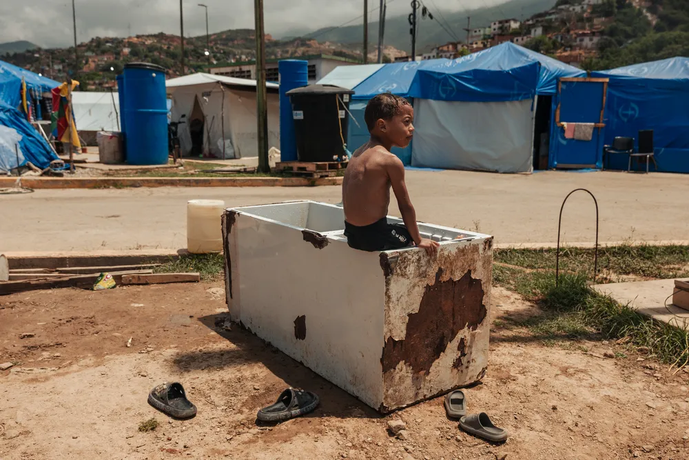 A young boy plays inside a ruined refrigerator