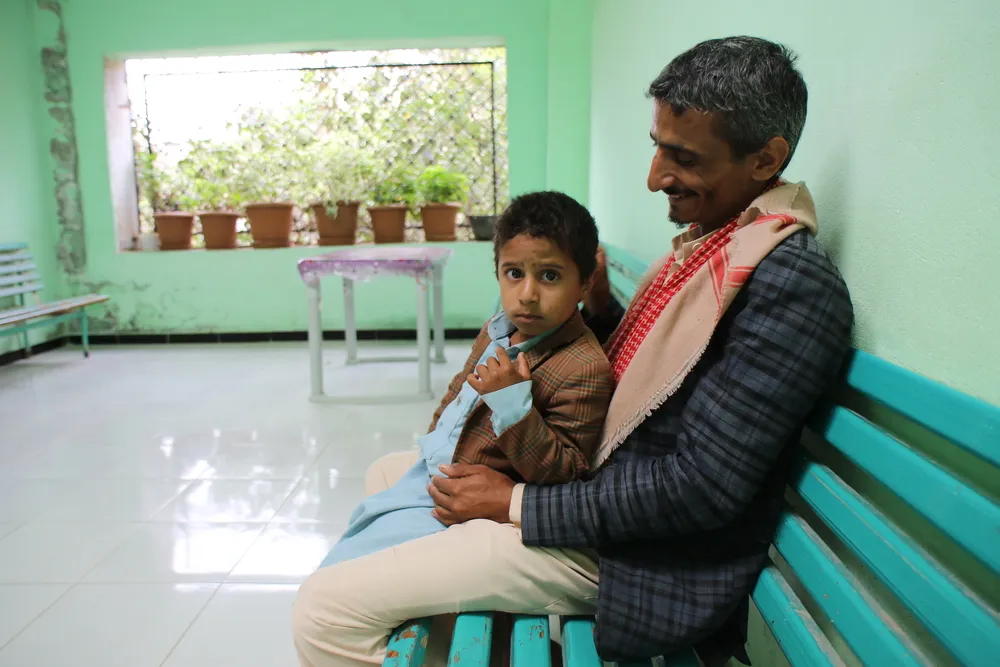Hamdan sitting with his son Hashid in the waiting area of the mental health clinic supported by MSF at Al-Gamhouri Hospital in Hajjah, Yemen. © Nasir Ghafoor/MSF 