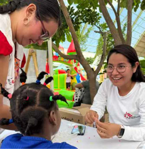 MSF staff talk to a little girl with braids