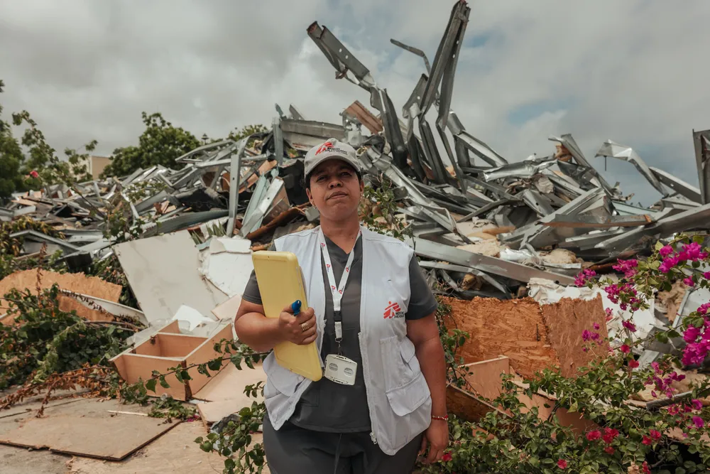 MSF community health worker Arelys walks past rows of demolished residential buildings